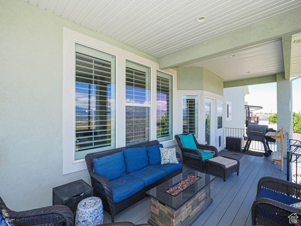 Wooden terrace featuring an outdoor living space with a fire pit and area for grilling