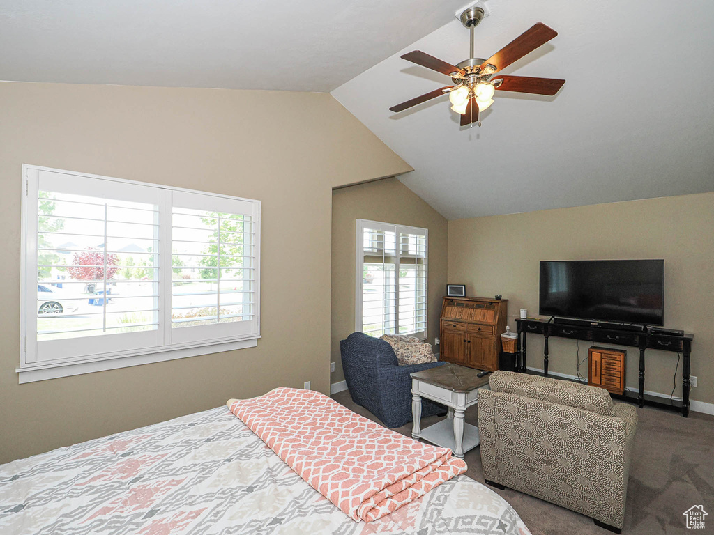 Carpeted bedroom with vaulted ceiling, baseboards, and a ceiling fan