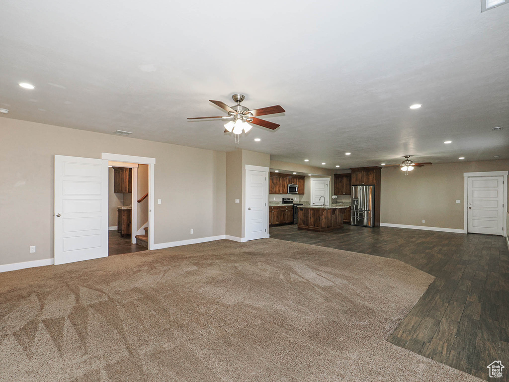 Unfurnished living room featuring ceiling fan, baseboards, recessed lighting, and stairway