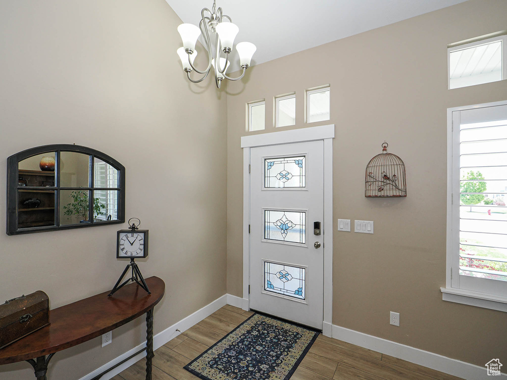 Entryway featuring light wood-style flooring, a chandelier, and baseboards