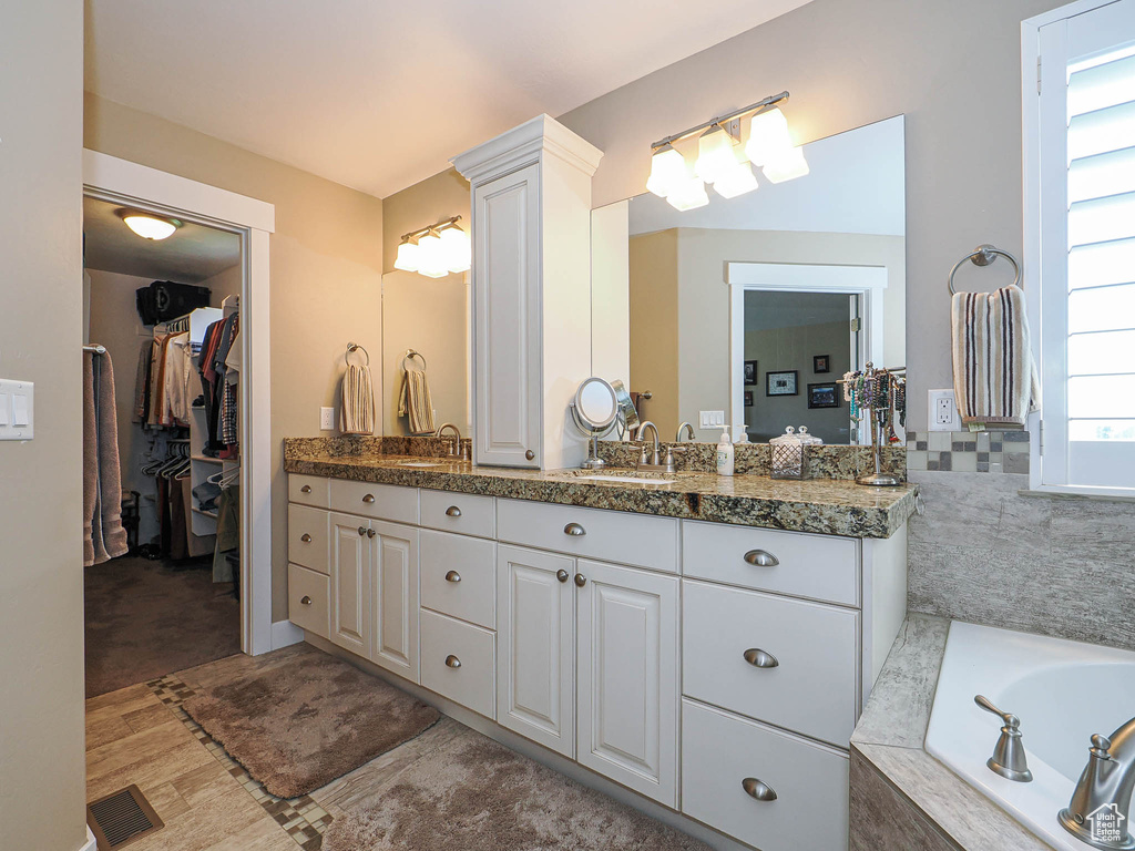 Bathroom featuring vanity, a bath, and a walk in closet