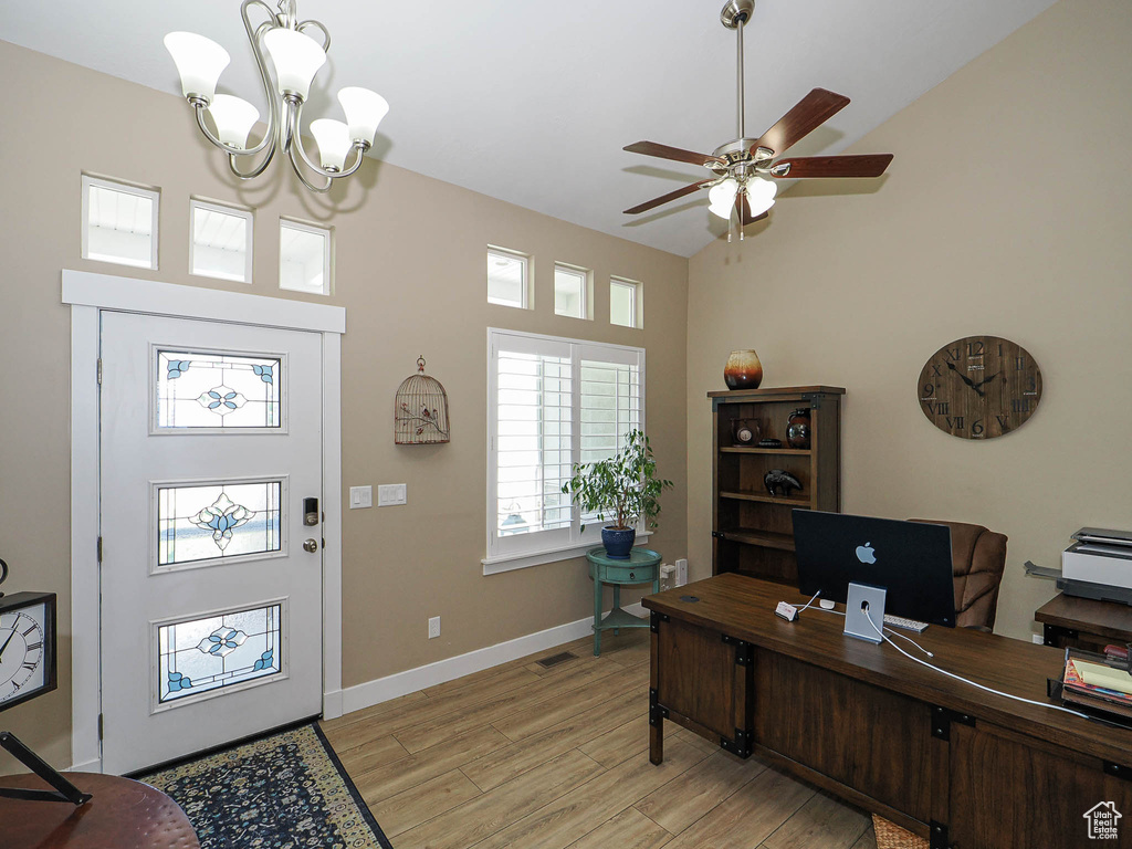 Office with light wood-type flooring, ceiling fan, a chandelier, a towering ceiling, and baseboards