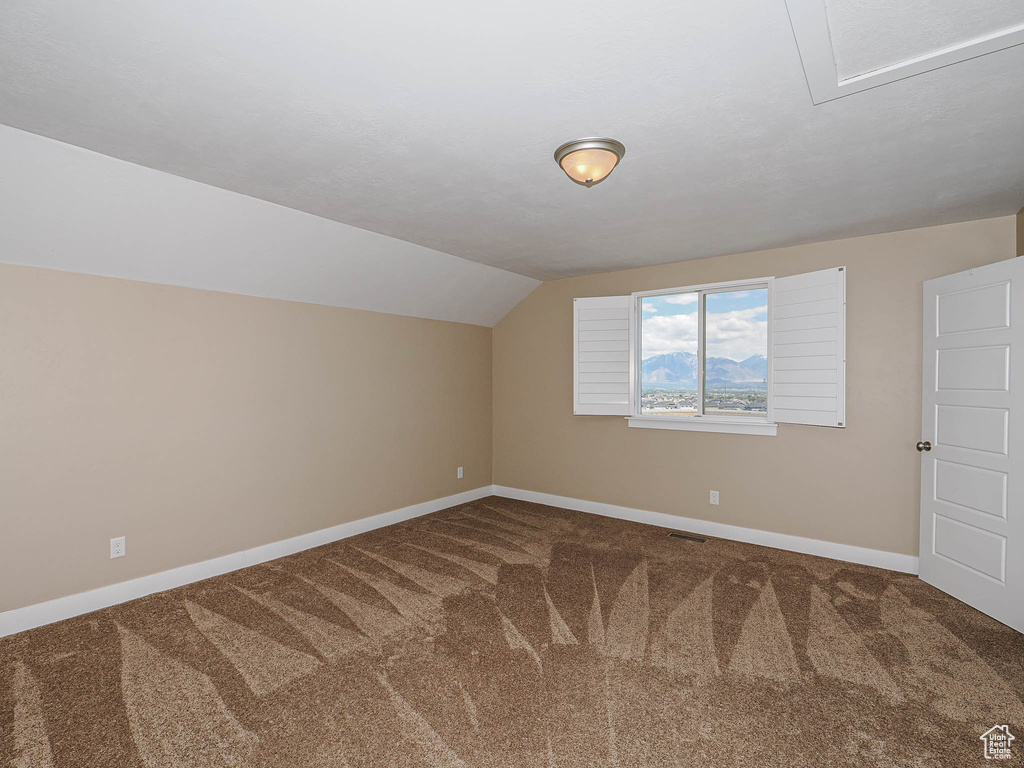 Additional living space featuring carpet, baseboards, and vaulted ceiling
