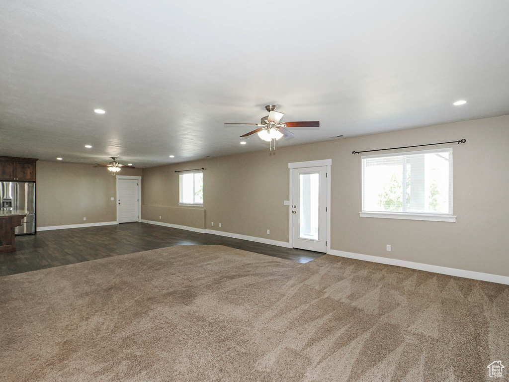 Unfurnished living room with a ceiling fan, recessed lighting, baseboards, dark colored carpet, and dark wood finished floors