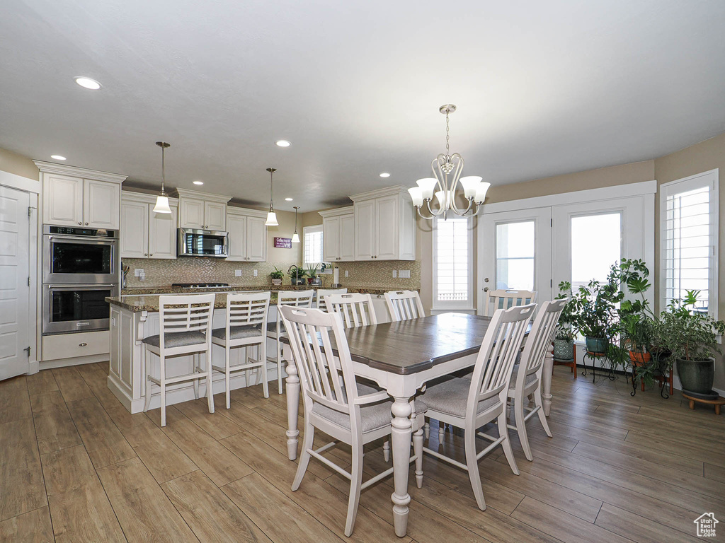 Dining area with a chandelier, plenty of natural light, light wood finished floors, and recessed lighting