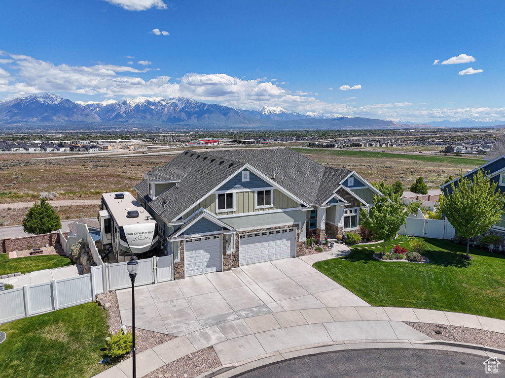 View of front facade featuring stone siding, driveway, a mountain view, board and batten siding, and a gate