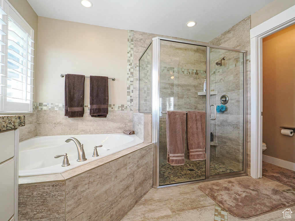 Bathroom featuring a bath, a stall shower, toilet, and recessed lighting