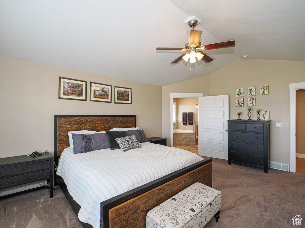 Bedroom with dark colored carpet, lofted ceiling, baseboards, a ceiling fan, and ensuite bath