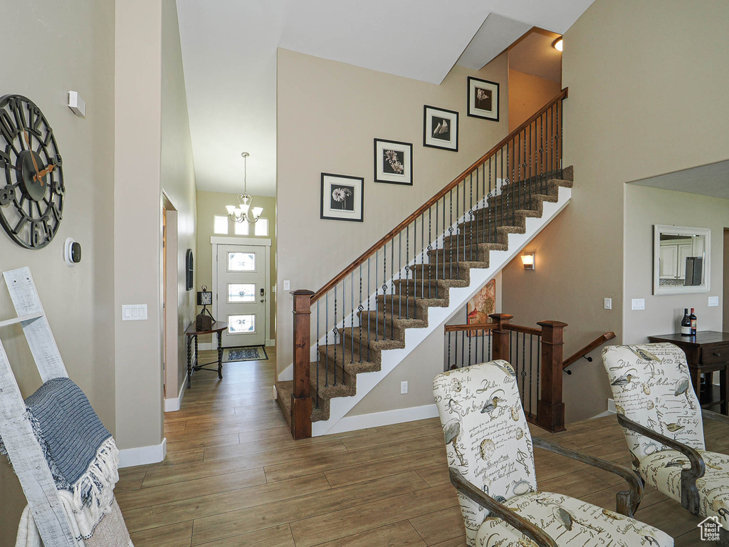 Entryway featuring wood finished floors, a chandelier, a towering ceiling, baseboards, and stairway