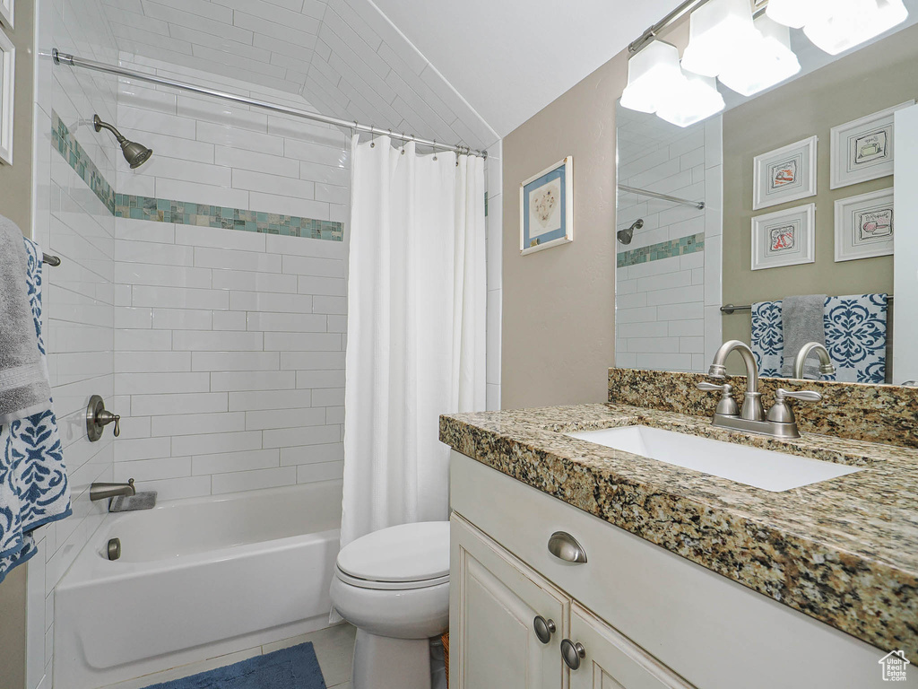 Bathroom featuring shower / bath combination with curtain, toilet, and vanity