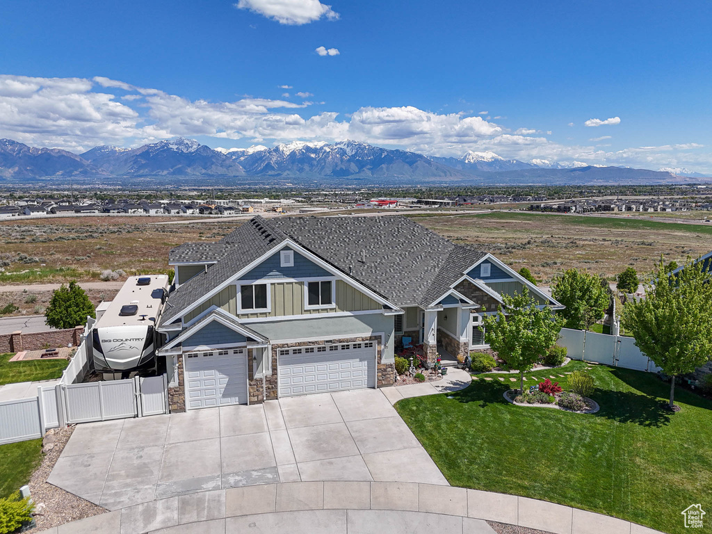 Craftsman house with stone siding, board and batten siding, a mountain view, driveway, and an attached garage