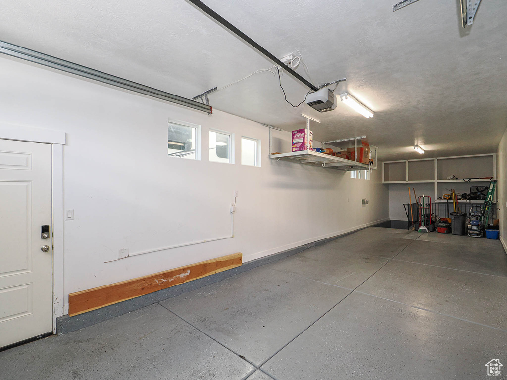Garage featuring a garage door opener and baseboards