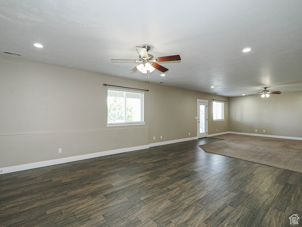 Unfurnished living room with ceiling fan, plenty of natural light, recessed lighting, and dark wood-type flooring