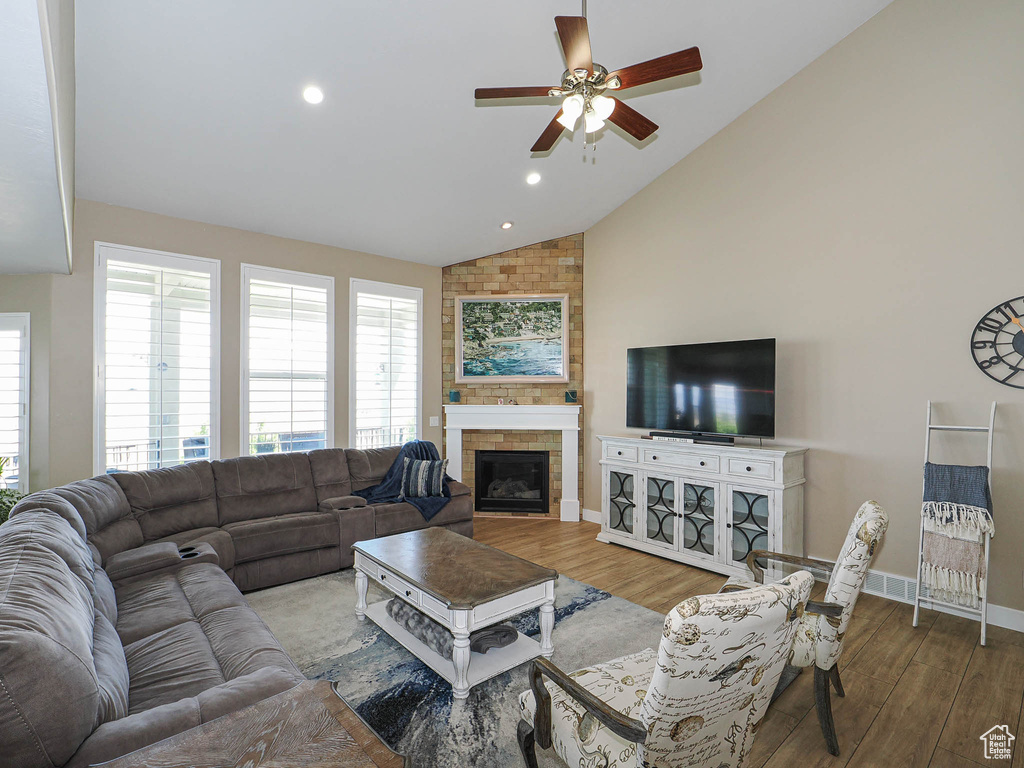 Living room featuring lofted ceiling, a ceiling fan, wood finished floors, baseboards, and a large fireplace