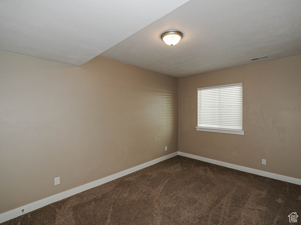Spare room with dark colored carpet and baseboards