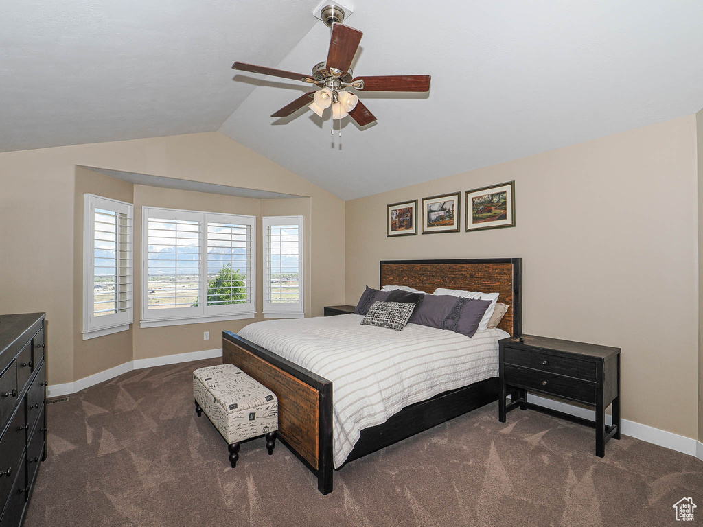 Bedroom featuring dark colored carpet, baseboards, lofted ceiling, and a ceiling fan