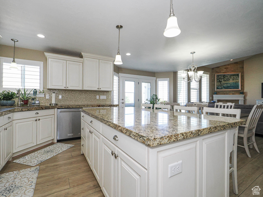 Kitchen with healthy amount of natural light, stainless steel dishwasher, a center island, a chandelier, and recessed lighting