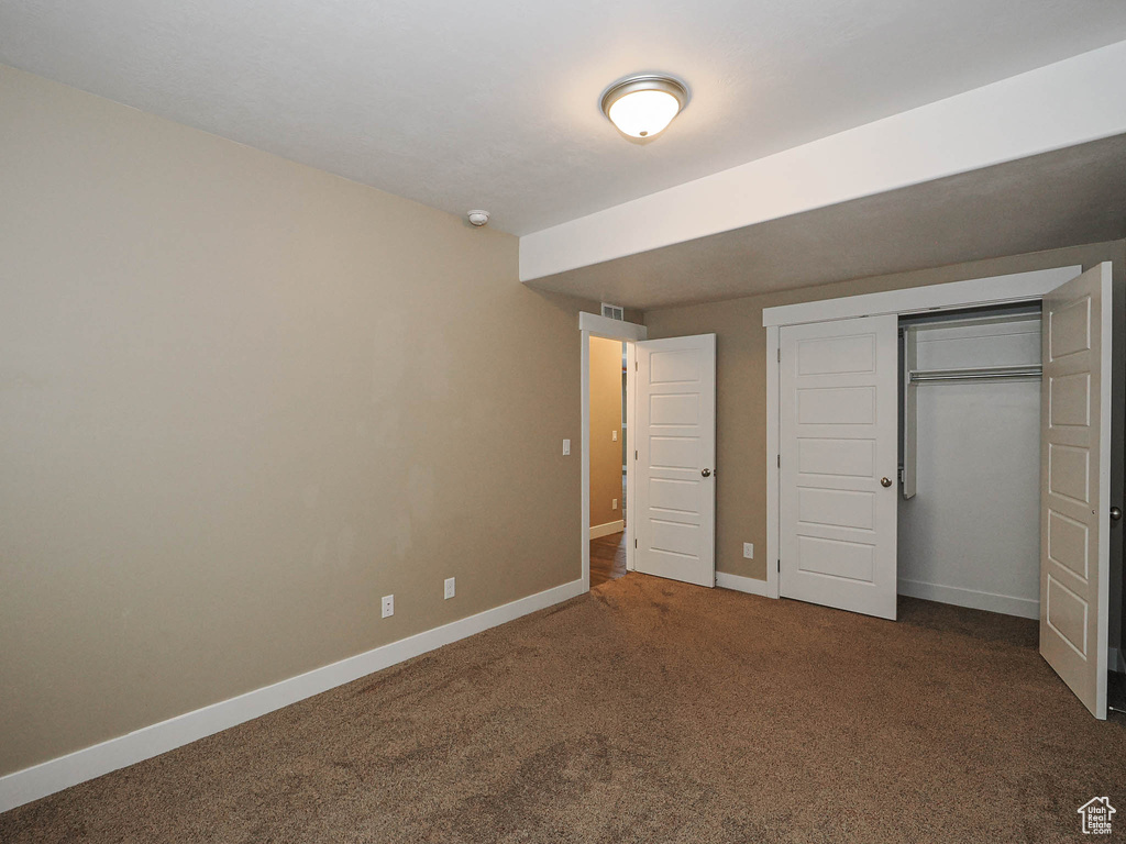 Unfurnished bedroom featuring carpet, baseboards, and a closet