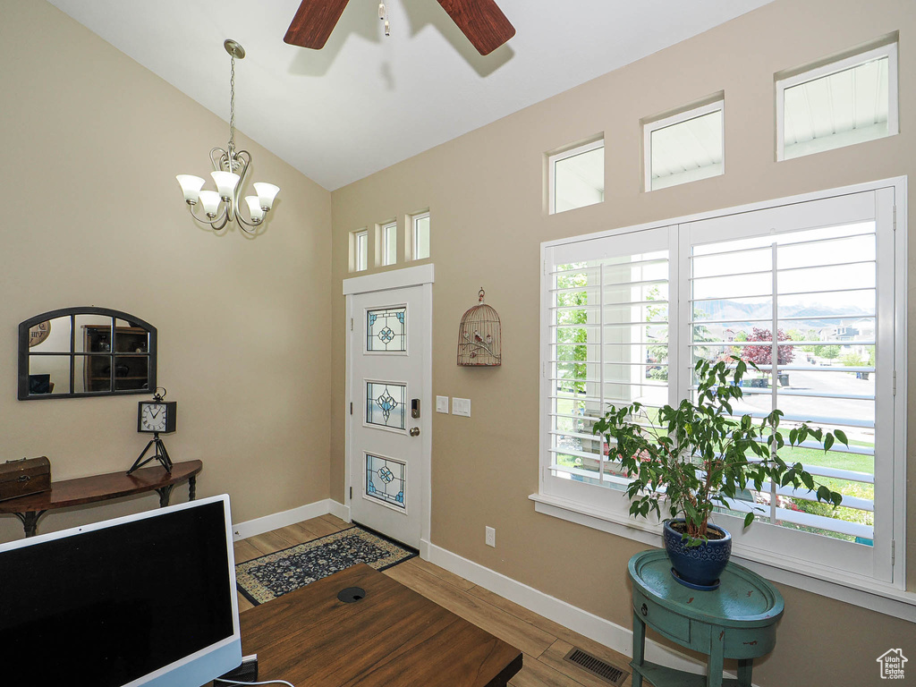 Entrance foyer with ceiling fan, wood finished floors, healthy amount of natural light, a chandelier, and high vaulted ceiling