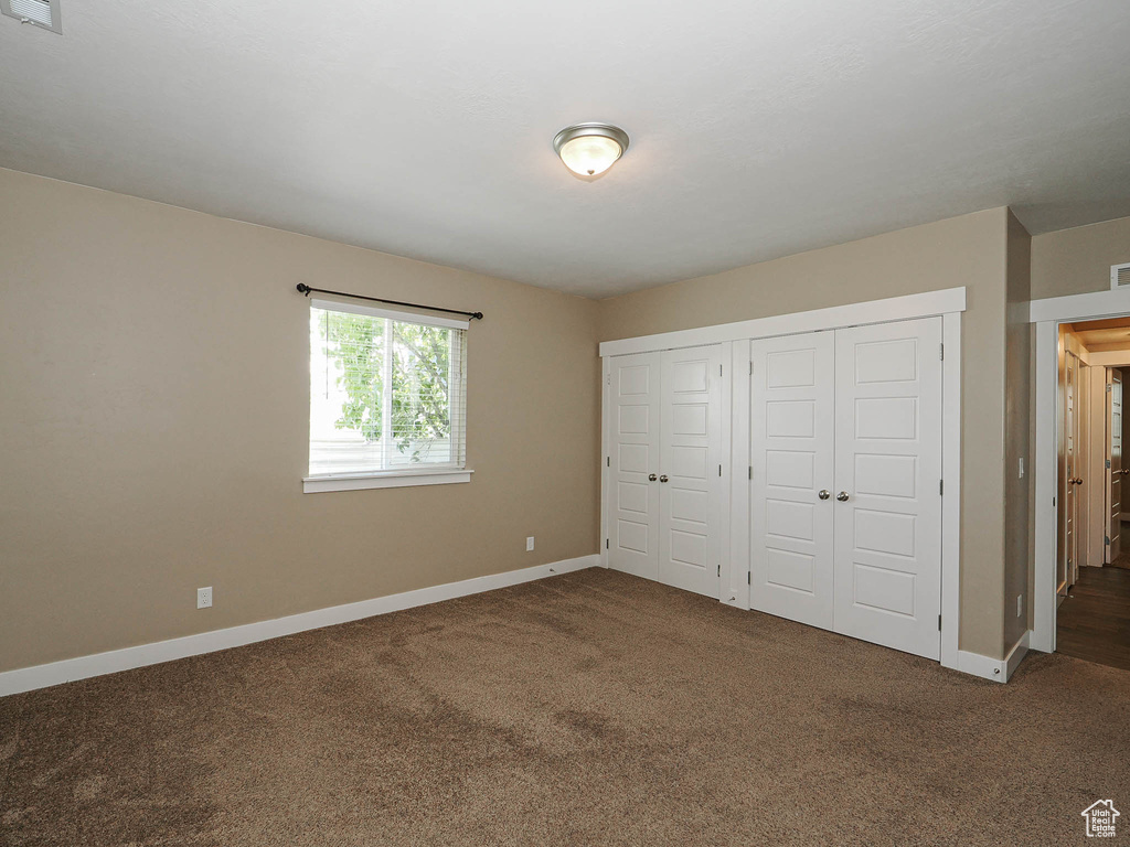 Unfurnished bedroom featuring carpet flooring, baseboards, and a closet