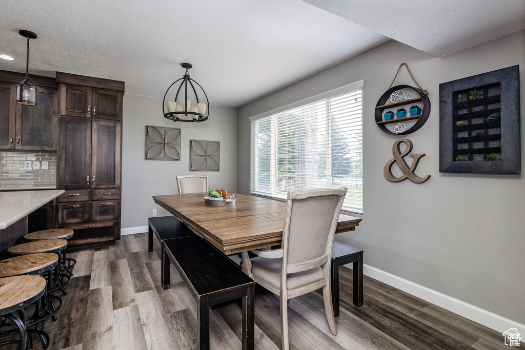 Dining space with baseboards, dark wood-style floors, and a chandelier