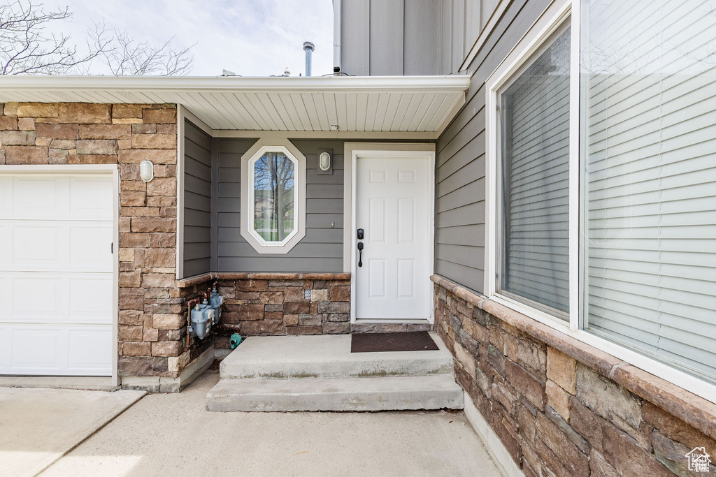 Property entrance featuring stone siding, a garage, and board and batten siding