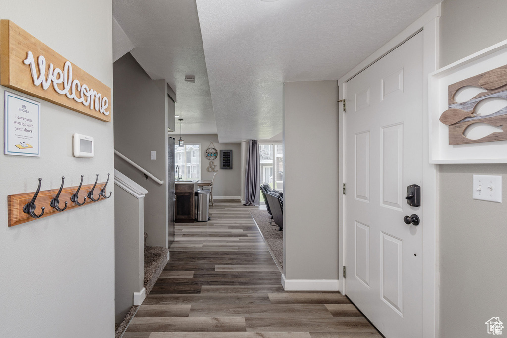 Hall featuring baseboards, wood finished floors, and stairs