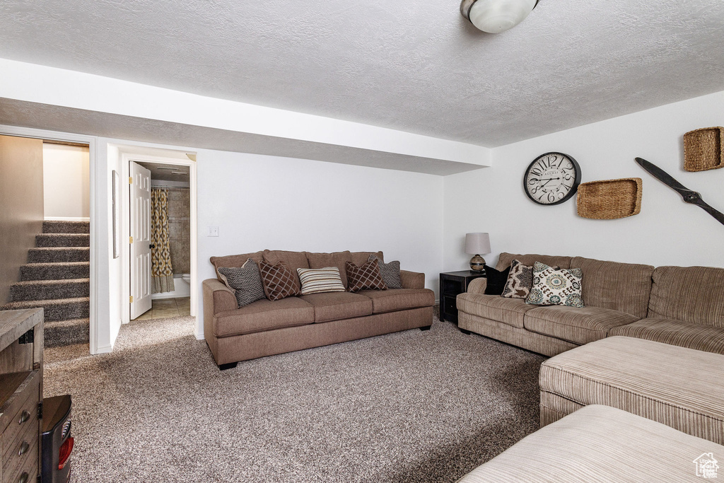 Living room featuring carpet floors, stairs, and a textured ceiling