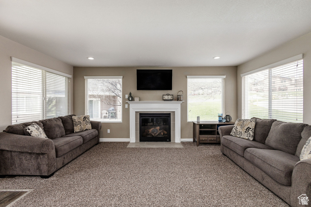 Living area with healthy amount of natural light, carpet floors, baseboards, a tiled fireplace, and recessed lighting