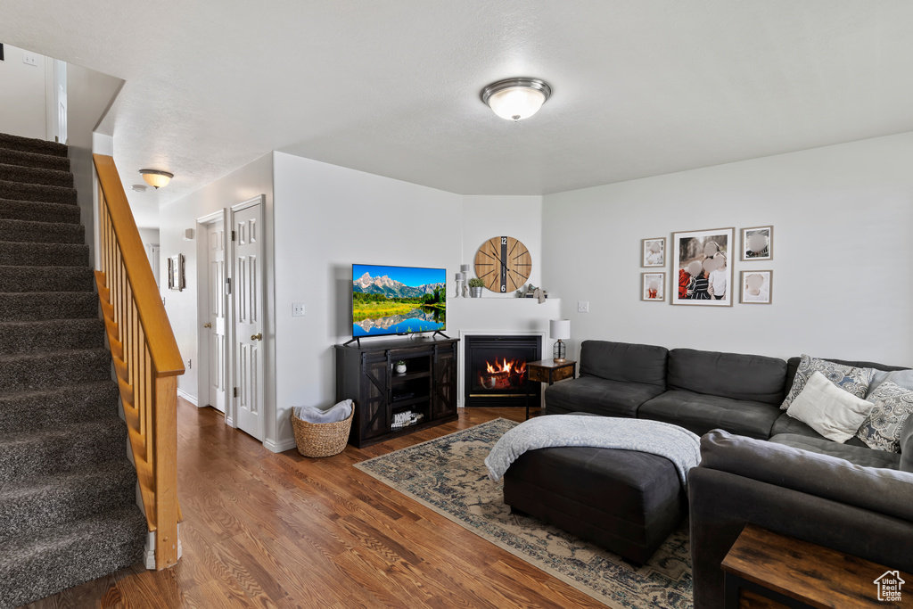 Living room with wood finished floors, stairs, and a lit fireplace