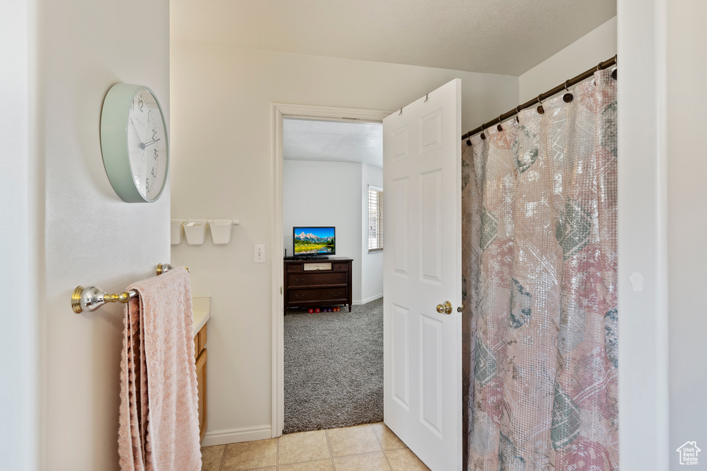 Bathroom with tile patterned floors, vanity, baseboards, and a shower with curtain