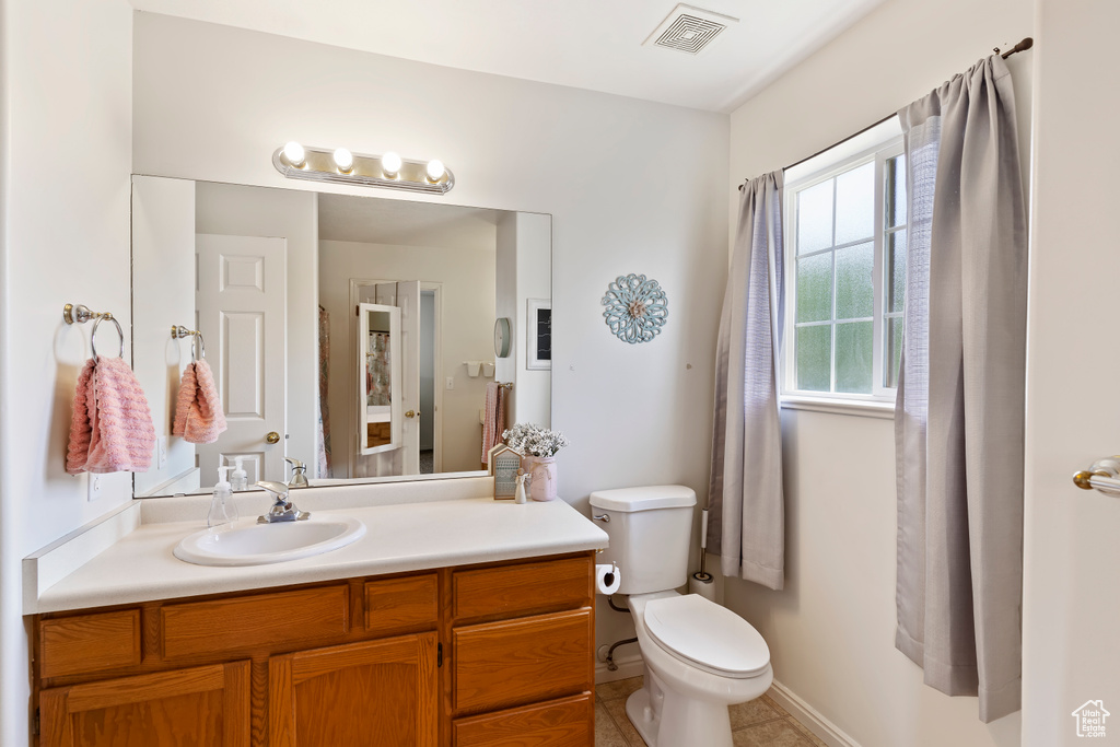 Bathroom featuring toilet, vanity, and tile patterned floors