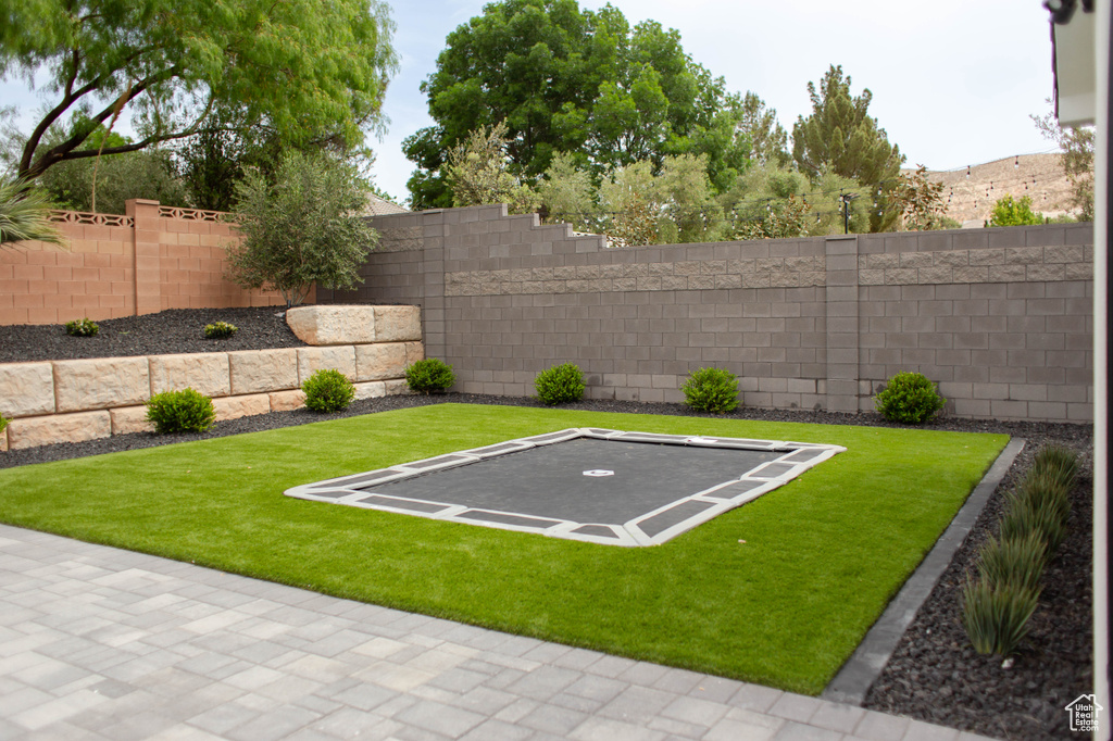 View of yard with a trampoline and a fenced backyard