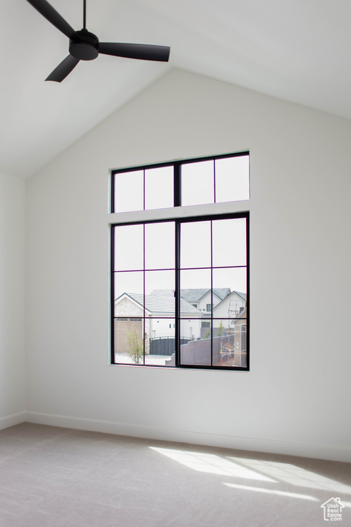 Carpeted spare room featuring ceiling fan, lofted ceiling, and baseboards