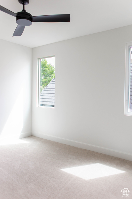 Carpeted spare room featuring baseboards and ceiling fan