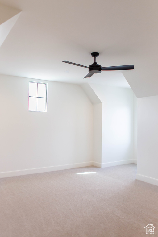 Additional living space with light colored carpet, lofted ceiling, baseboards, and a ceiling fan