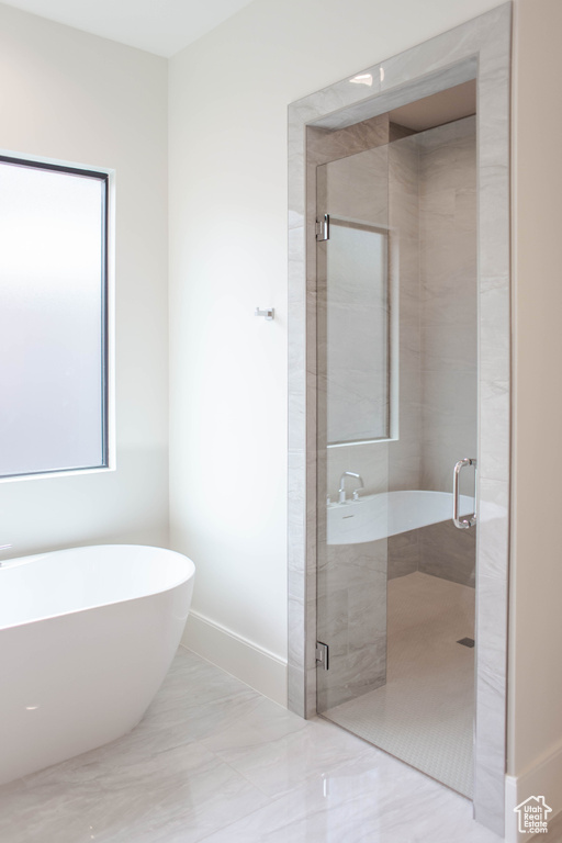 Full bath featuring a soaking tub, baseboards, and a shower stall