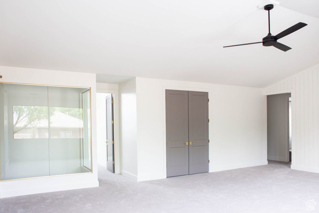 Unfurnished bedroom with baseboards, light carpet, ceiling fan, and vaulted ceiling