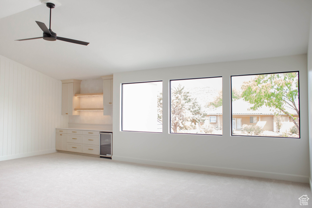 Unfurnished bedroom with light colored carpet, baseboards, and beverage cooler