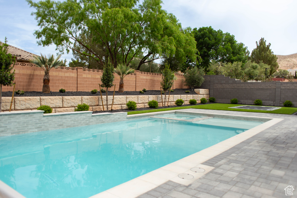 View of swimming pool with an in ground hot tub, a fenced in pool, and a fenced backyard