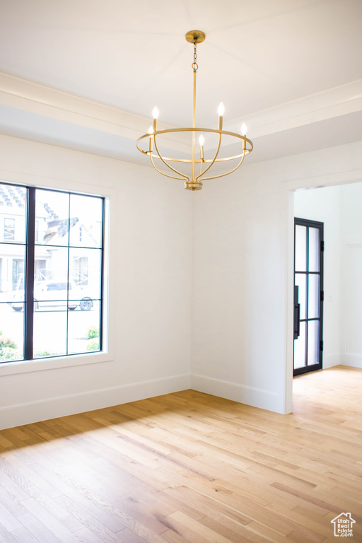 Unfurnished room with an inviting chandelier, baseboards, and light wood-style floors
