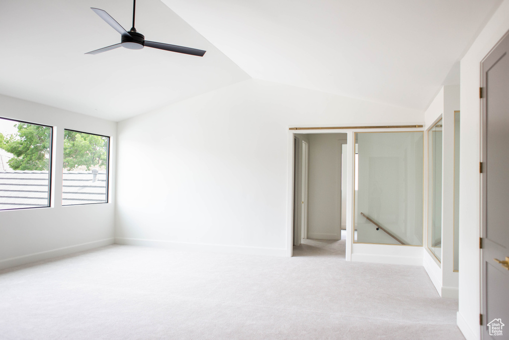 Unfurnished bedroom with vaulted ceiling, light carpet, baseboards, and a ceiling fan