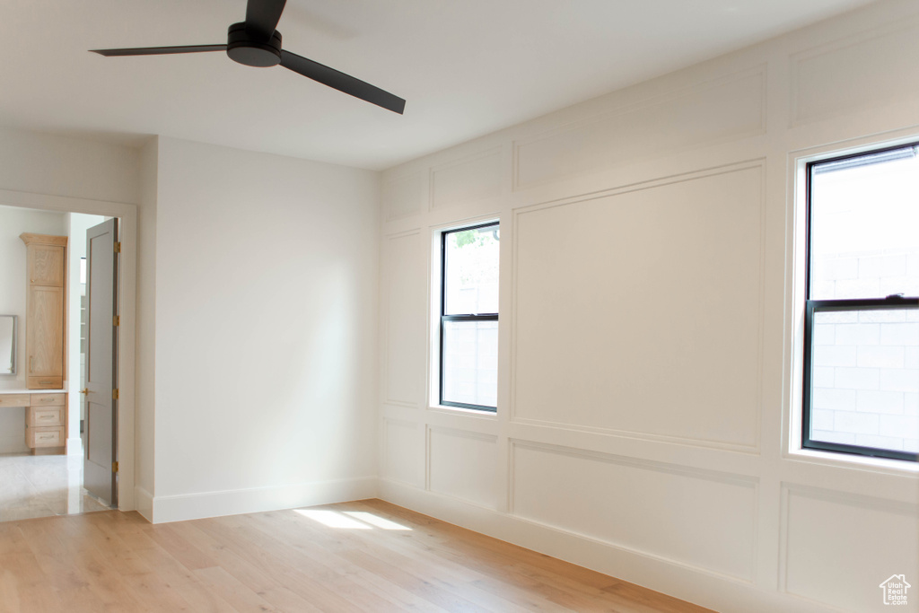 Empty room featuring light wood finished floors, a decorative wall, and a ceiling fan