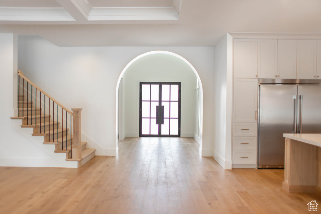 Foyer featuring stairway, arched walkways, light wood-type flooring, and baseboards