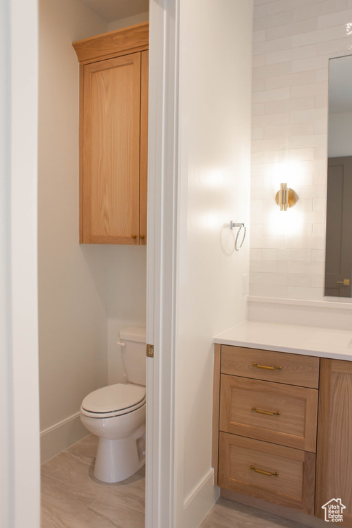 Bathroom with baseboards, vanity, toilet, and wood finished floors