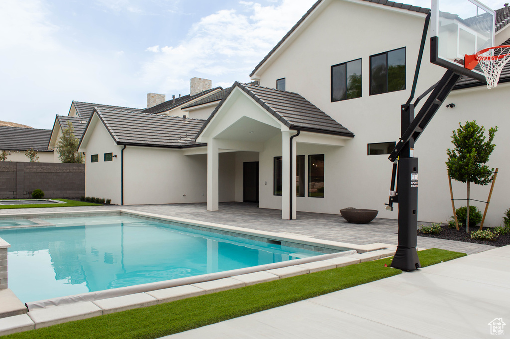Rear view of house featuring a tile roof, a patio area, stucco siding, and fence