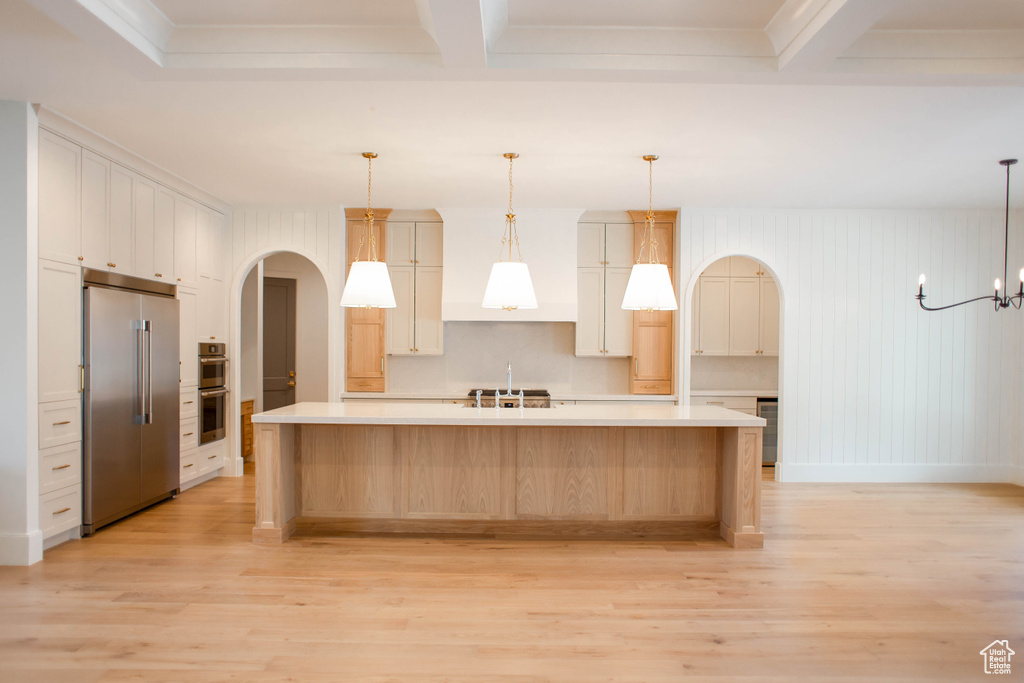 Kitchen featuring stainless steel appliances, arched walkways, light countertops, and light wood-style floors