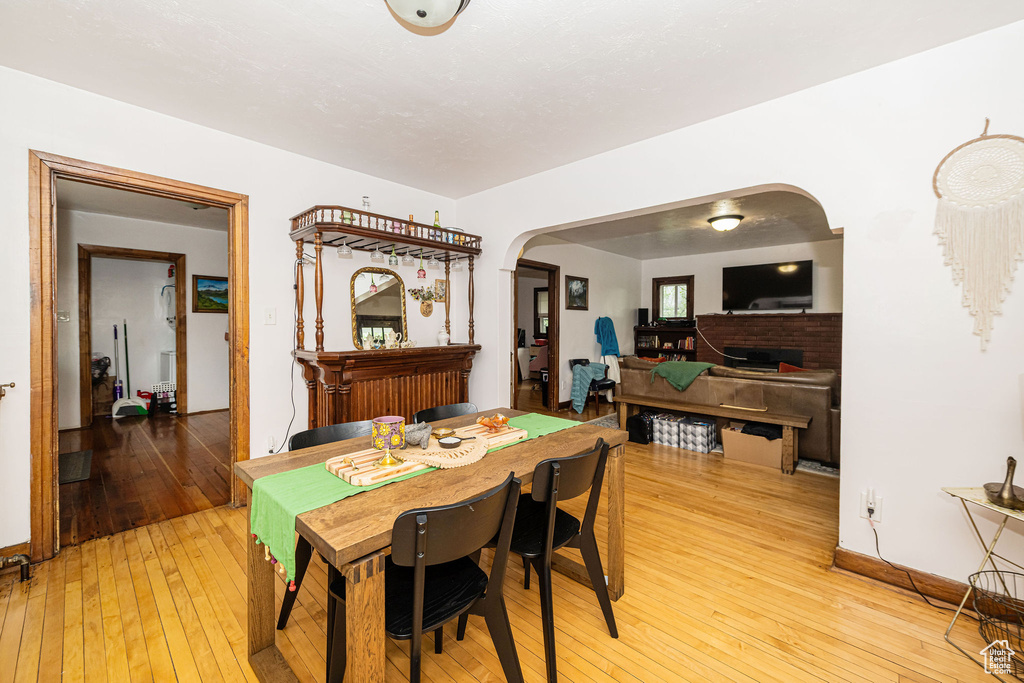 Dining area with arched walkways, light wood-style floors, and baseboards