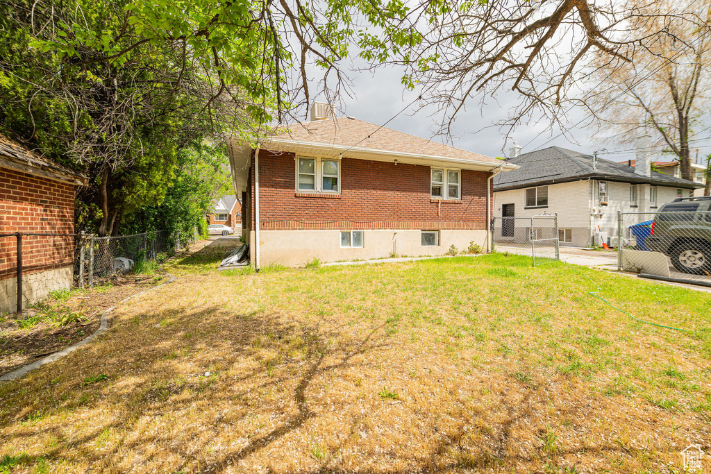 Back of property featuring brick siding and roof with shingles