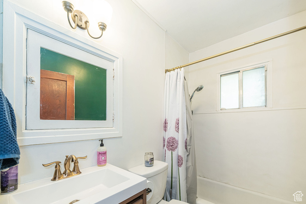 Bathroom featuring toilet, vanity, and shower / bath combo